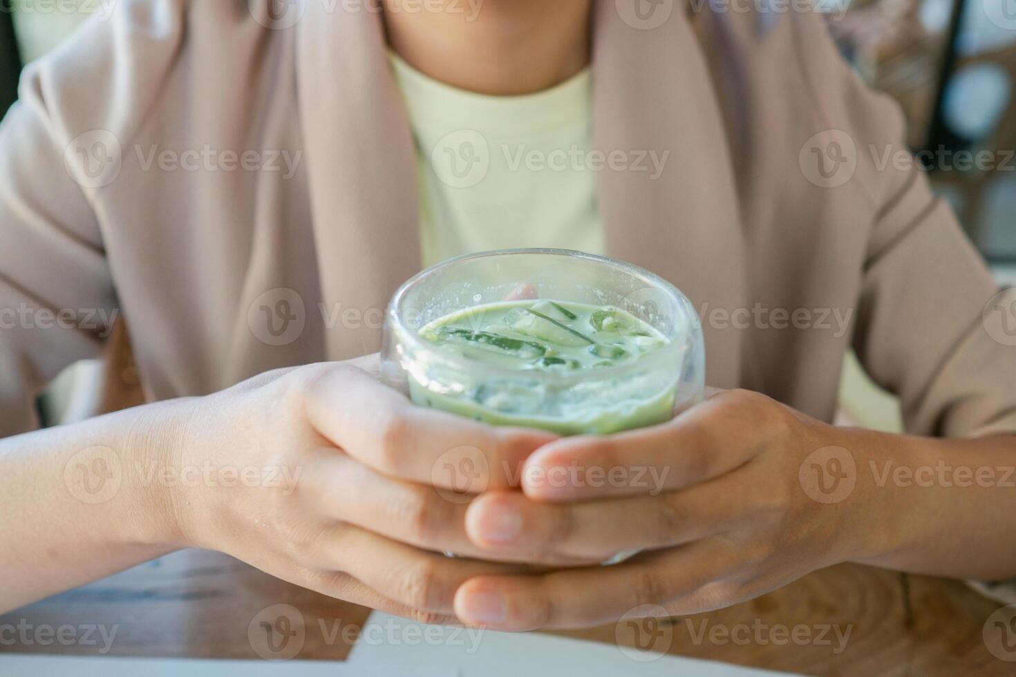 A person holding a refreshing iced matcha latte, showcasing a cozy and relaxed cafe atmosphere. photo