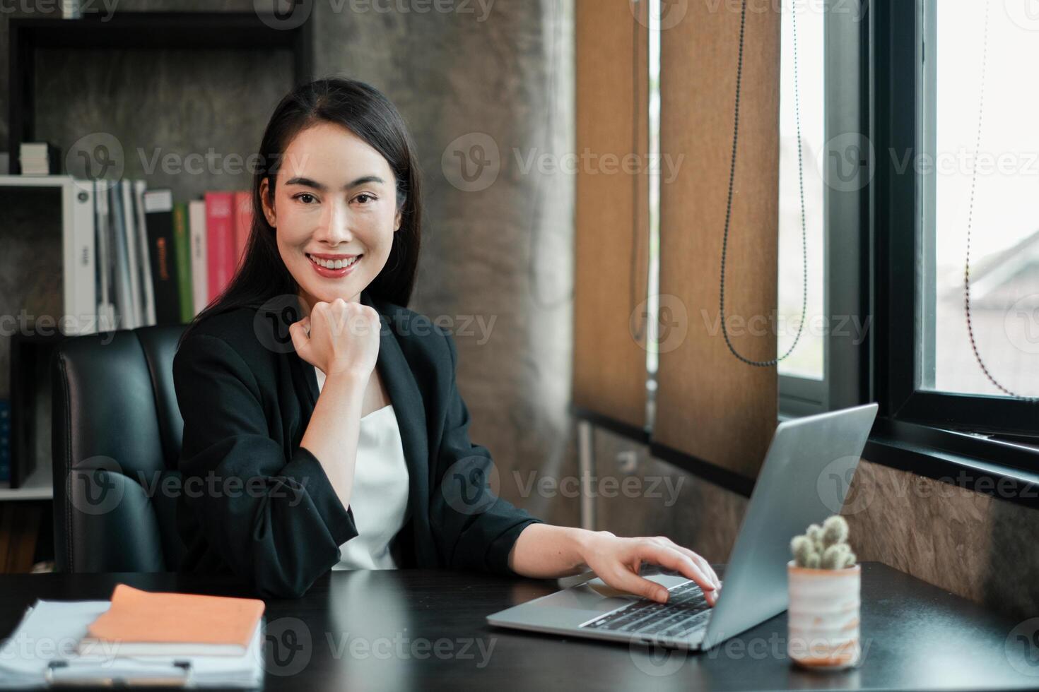 Professional woman in a sleek office environment, using a laptop, exuding confidence and success. photo