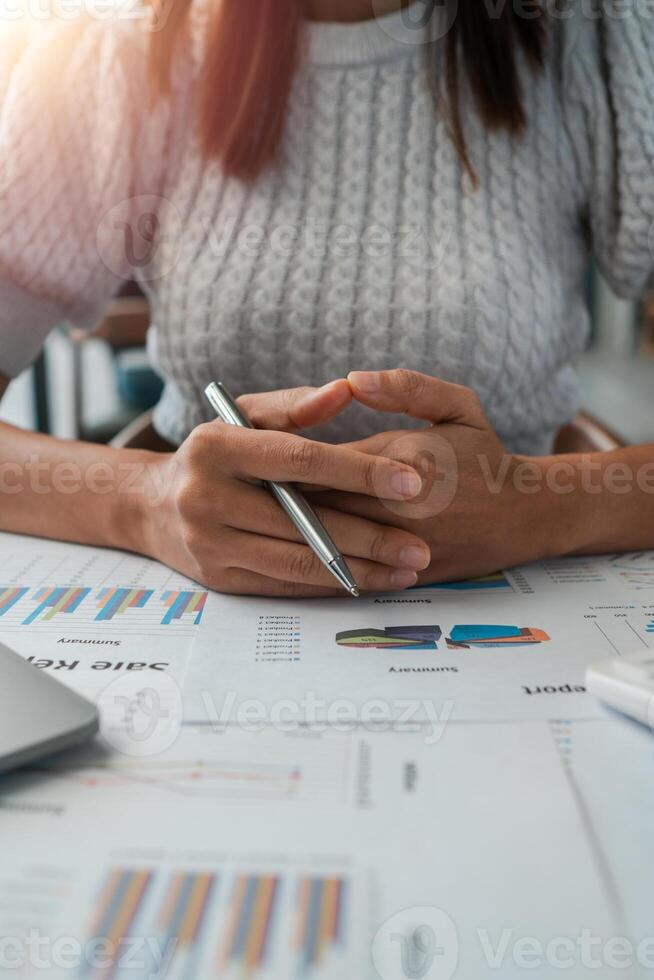 Close-up of a businesswoman reviewing financial documents with charts and graphs, highlighting data analysis and corporate strategy. photo