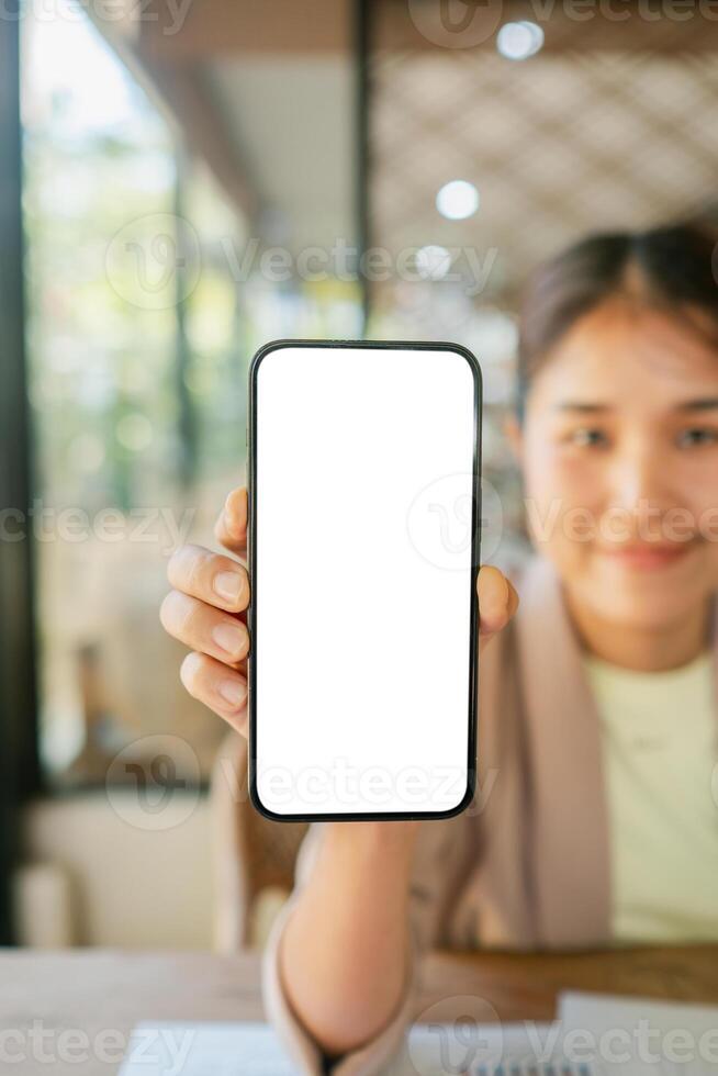 Smiling woman in a cafe showing a smartphone with a blank screen, perfect for app or website mockup presentations. photo