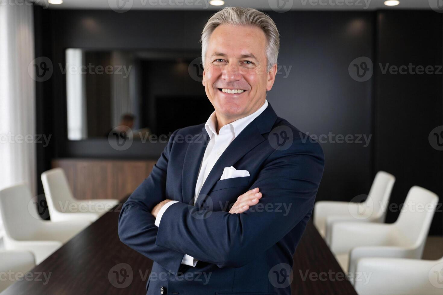A man in a suit standing in front of a conference table photo