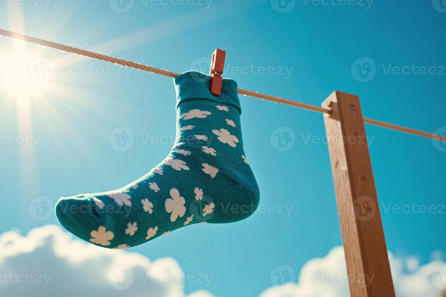 A sock hanging on a clothesline with the sun in the background photo