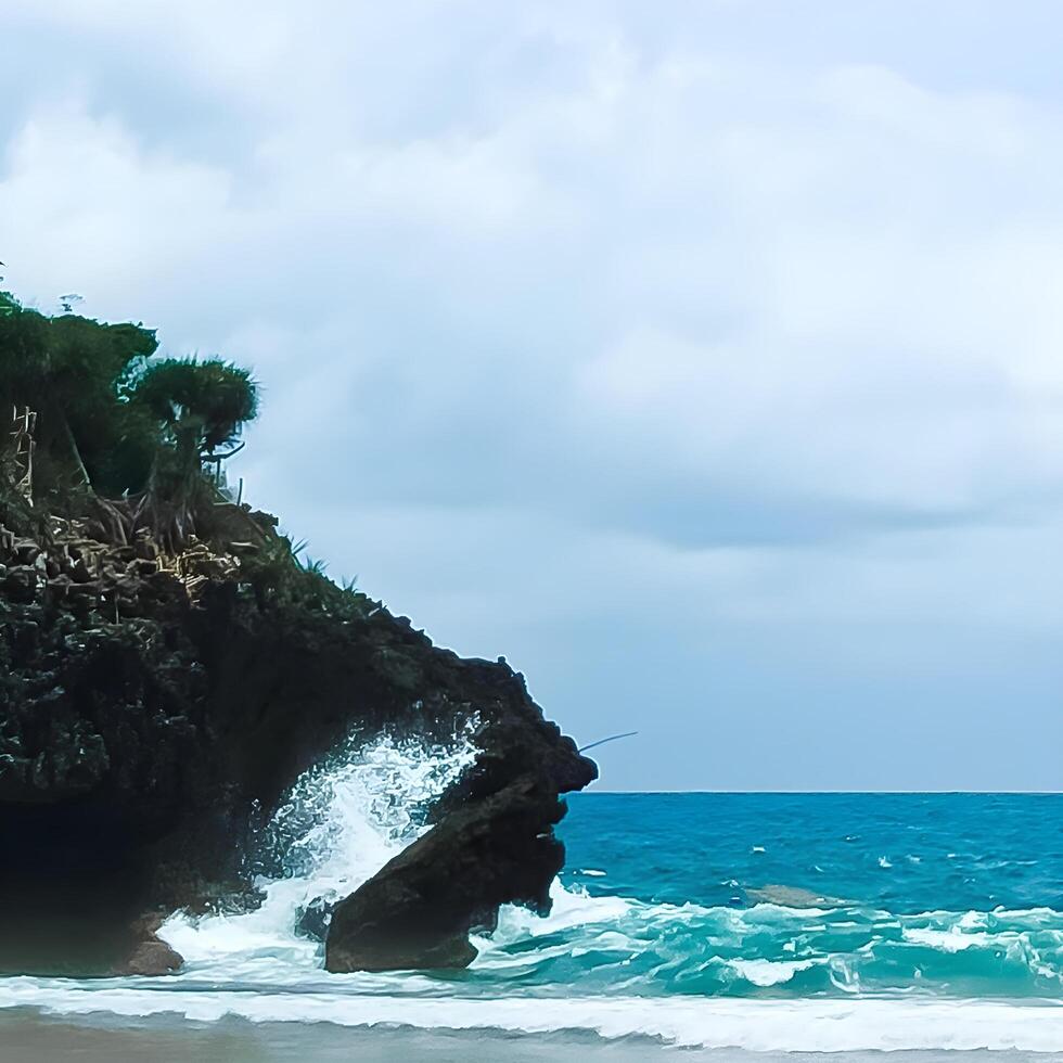 A man is standing on the beach near a rock formation photo