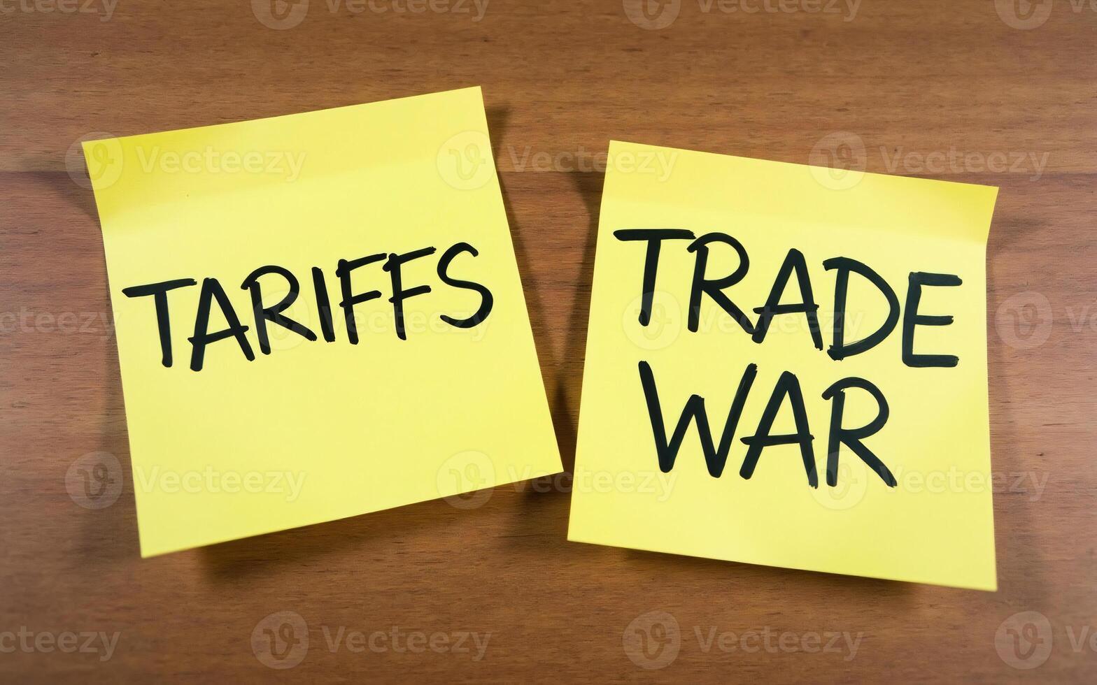 Tariffs reminder two yellow sticky note with the word TARIFFS and TRADE WAR handwritten in black on a wooden surface, Symbolizing trade conflict photo