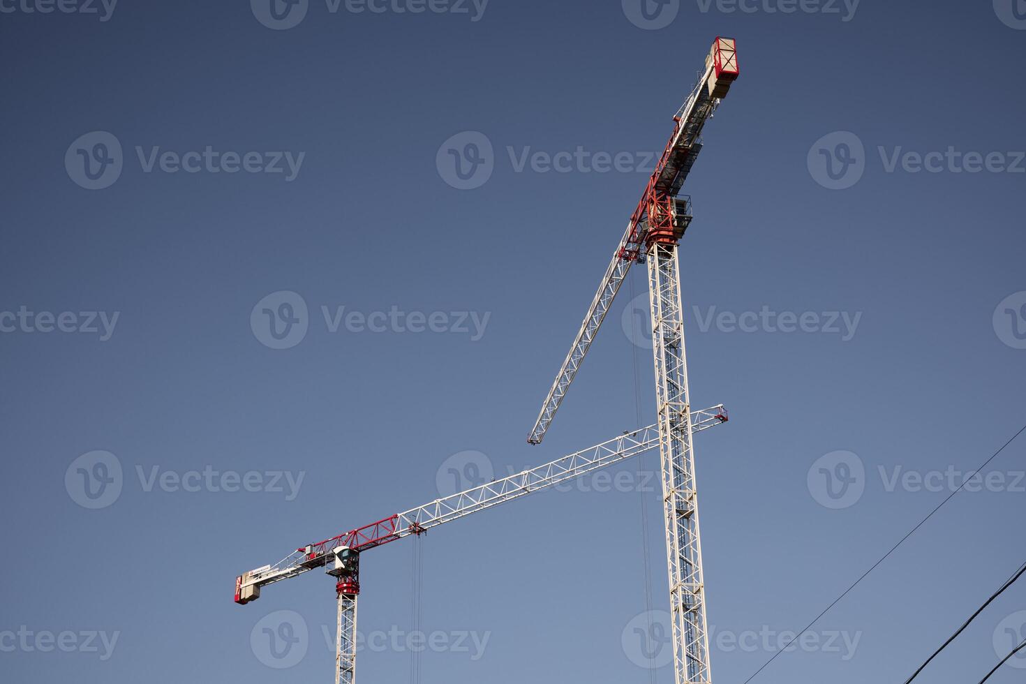 Construction Cranes Set Against a Beautiful, Clear Blue Sky in a Thriving Urban Landscape photo