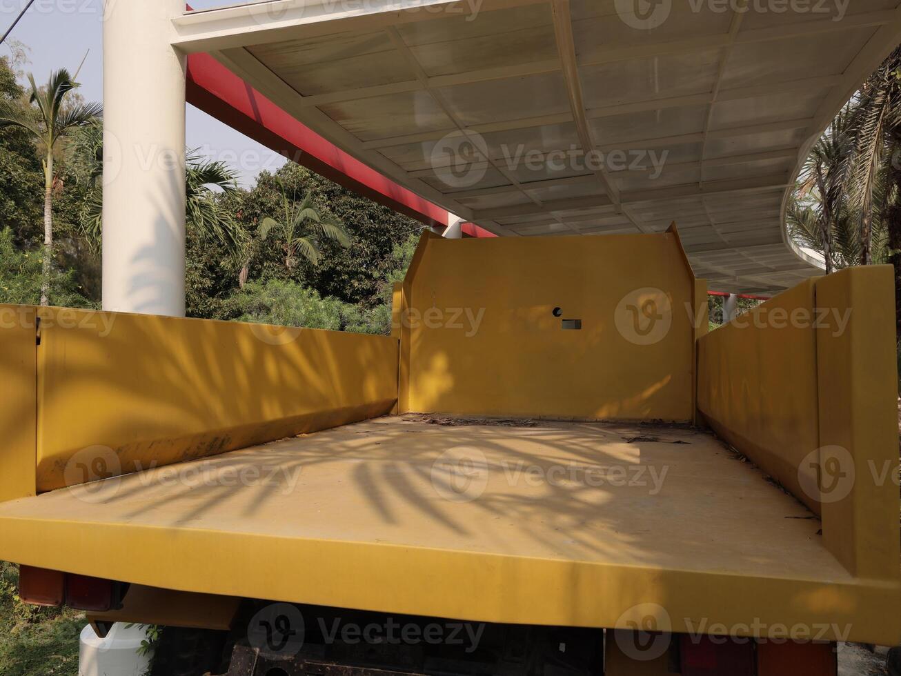 A Bright Yellow Empty Truck Bed Sitting in a Beautiful and Lush Green Environment photo