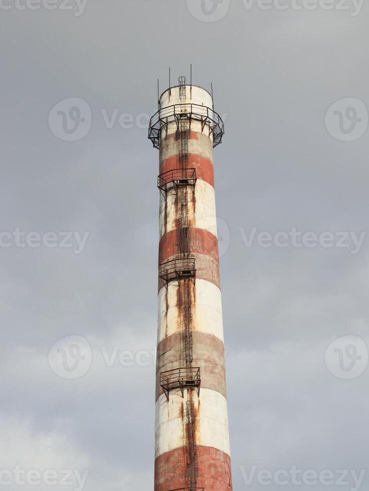 A towering Industrial Smokestack is beautifully set against a dramatic, cloudy sky backdrop photo