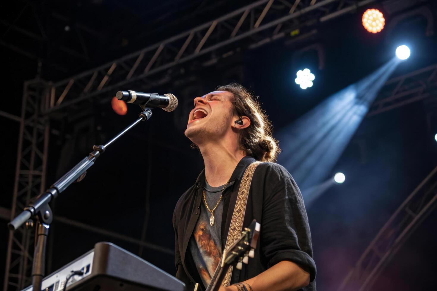musician on stage passionately performing with microphone and guitar, immersed in music and energy of crowd. vibrant lights enhance atmosphere of live concert photo