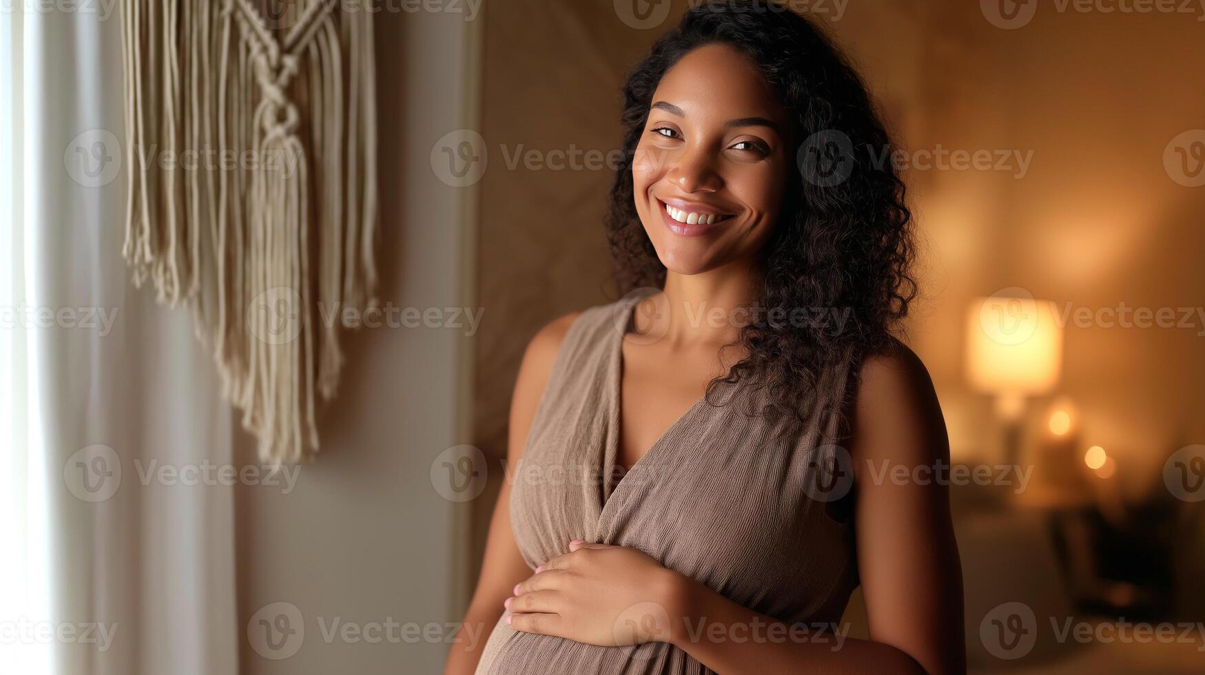 A pregnant Latina woman stands in a warmly lit living room, gently holding her belly while smiling. The atmosphere radiates warmth and anticipation. photo
