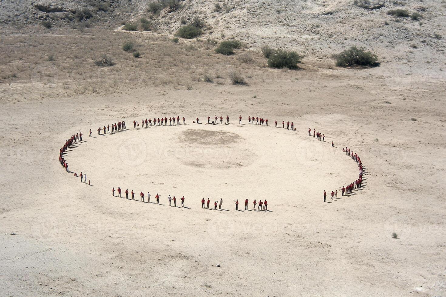 A group of people standing in a circle in the desert photo