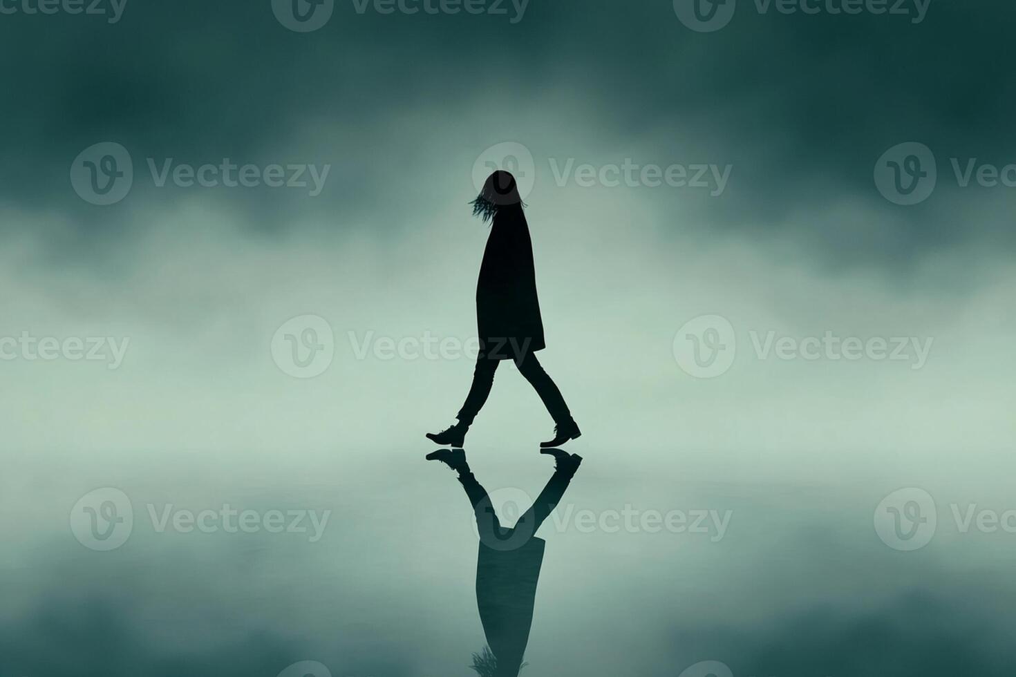 A silhouette of a woman walking on a foggy surface photo