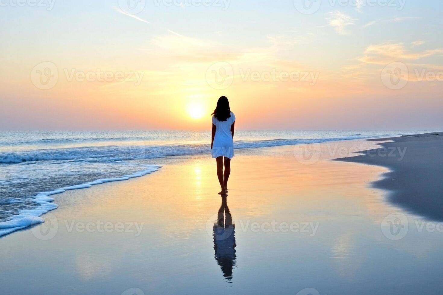 A woman walking on the beach at sunset photo