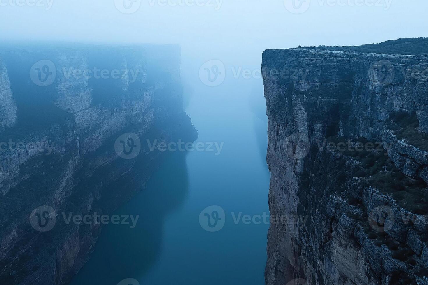 A man stands on a cliff overlooking a river photo