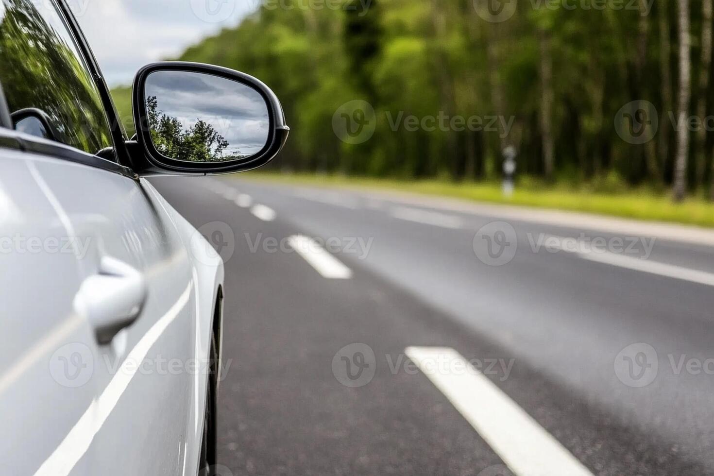 A car is driving down the road with its side mirror photo
