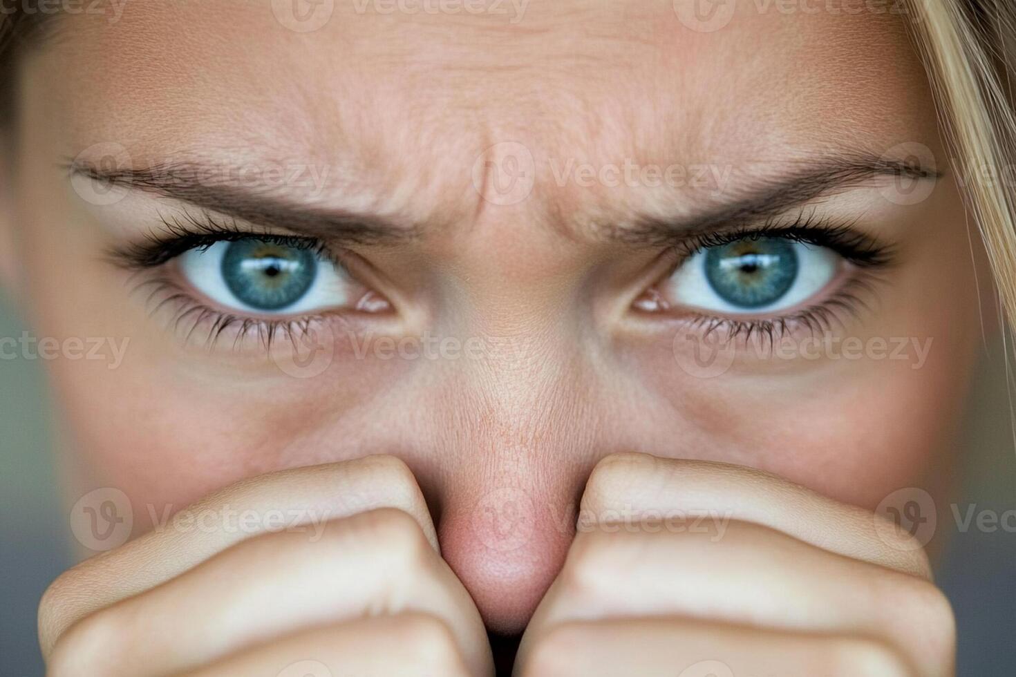 A woman with blue eyes covering her nose photo