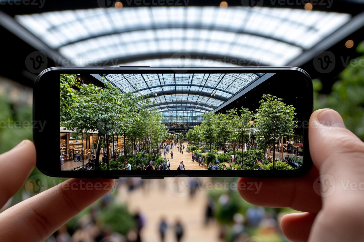 A person holding up a smartphone with a view of a large indoor shopping mall photo