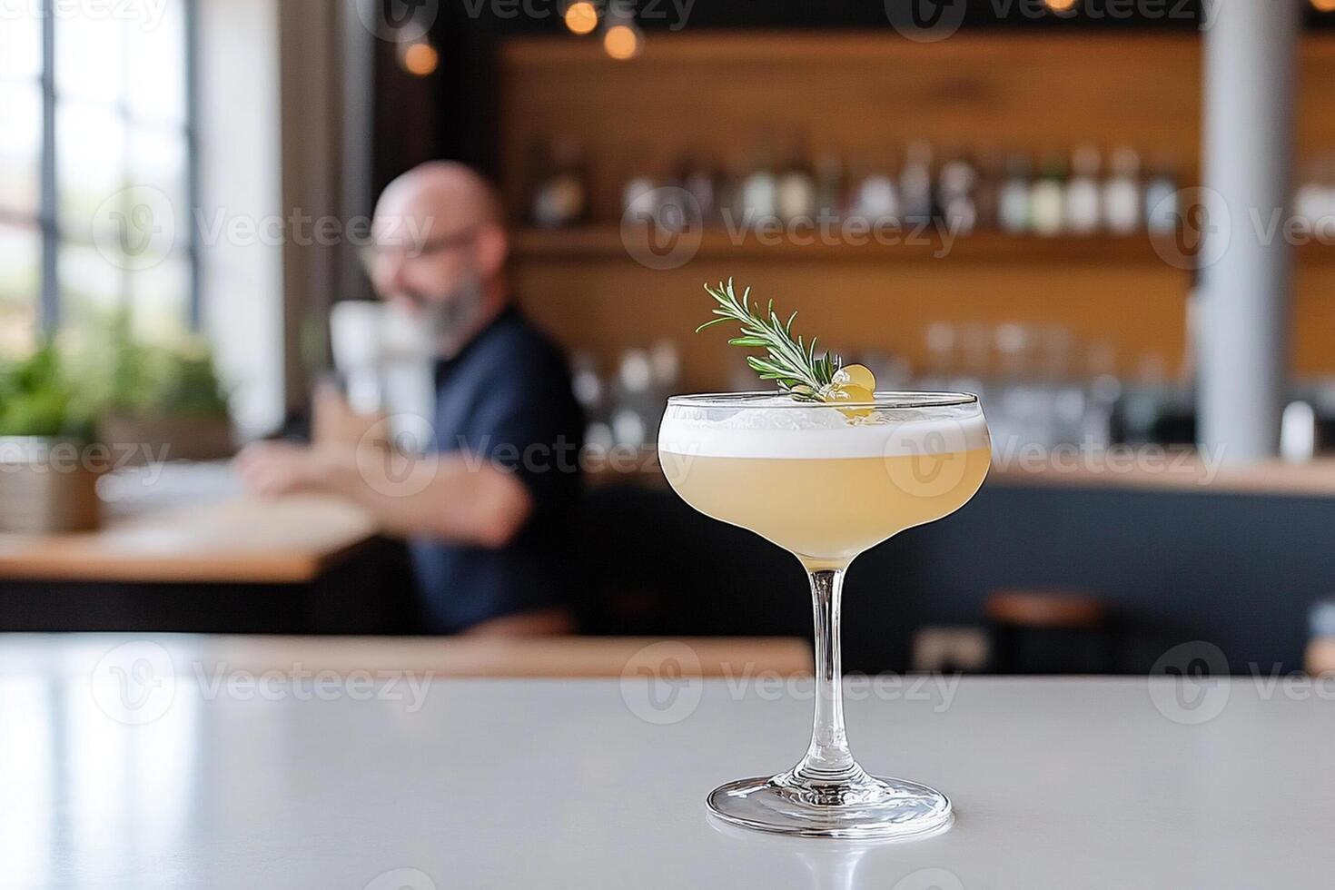 A cocktail sitting on a bar with a man behind the bar photo