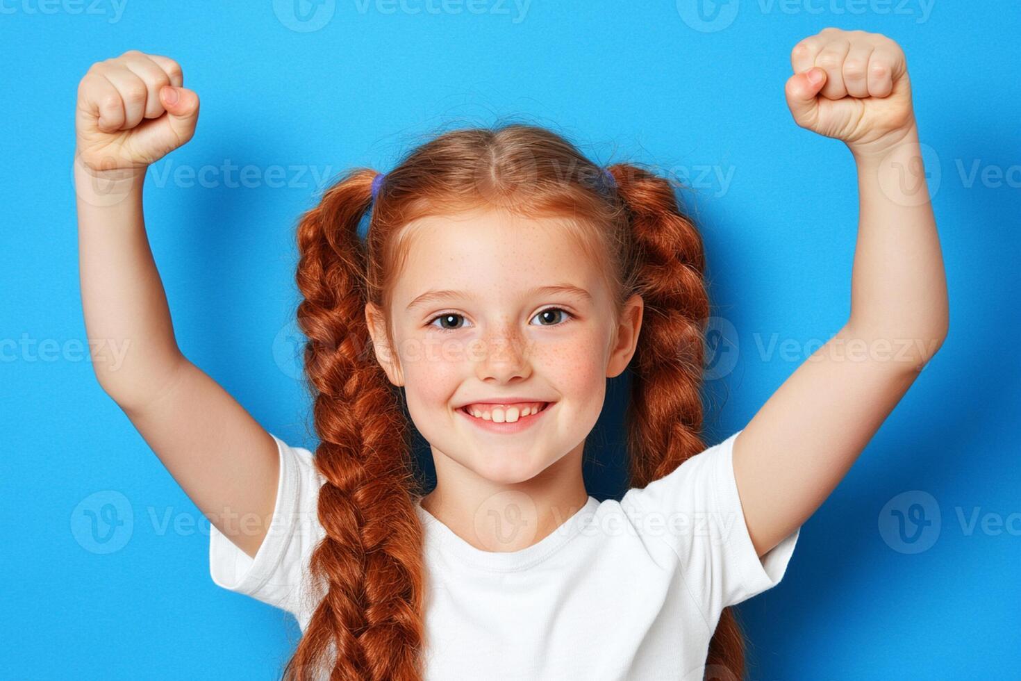 A little girl with red hair and braids is raising her arms photo