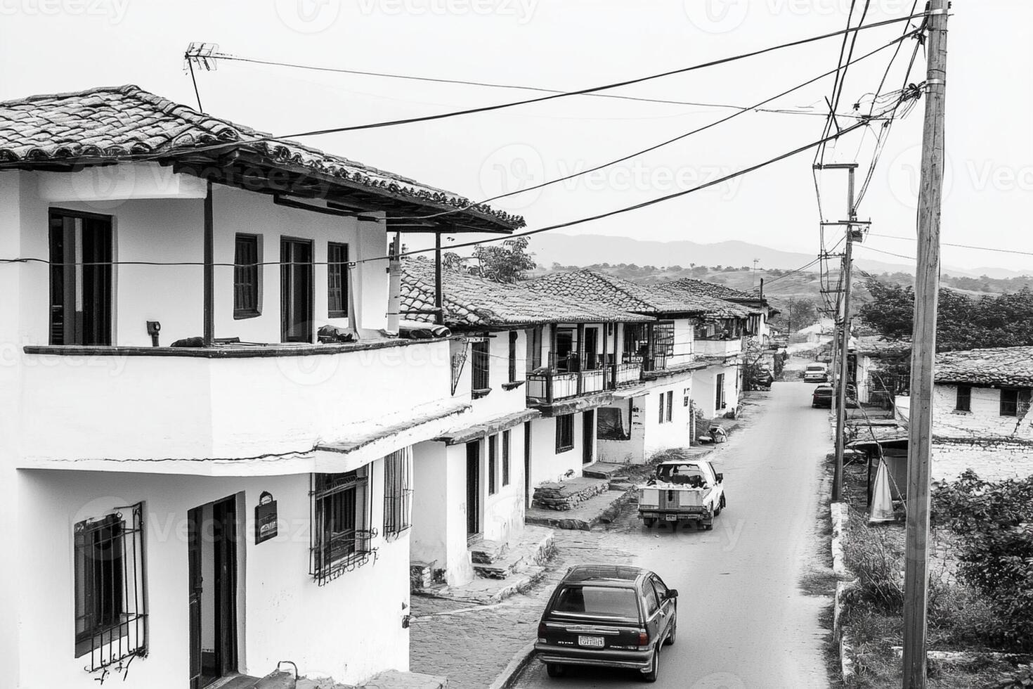 A black and white photo of a street with cars parked on it