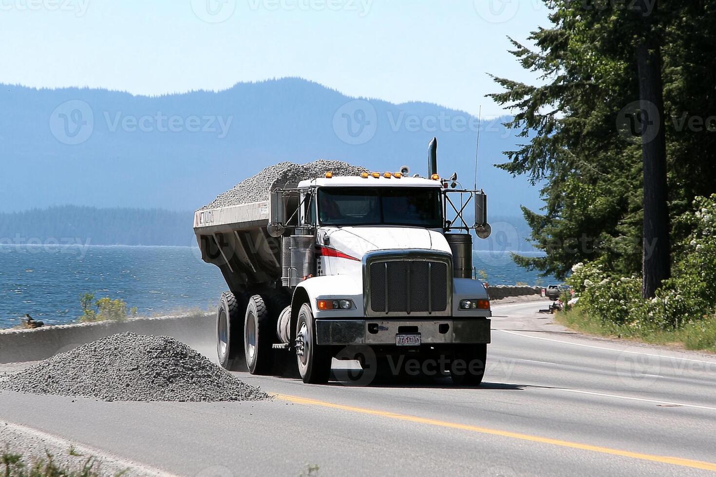 A dump truck driving down a road with a mountain in the background photo