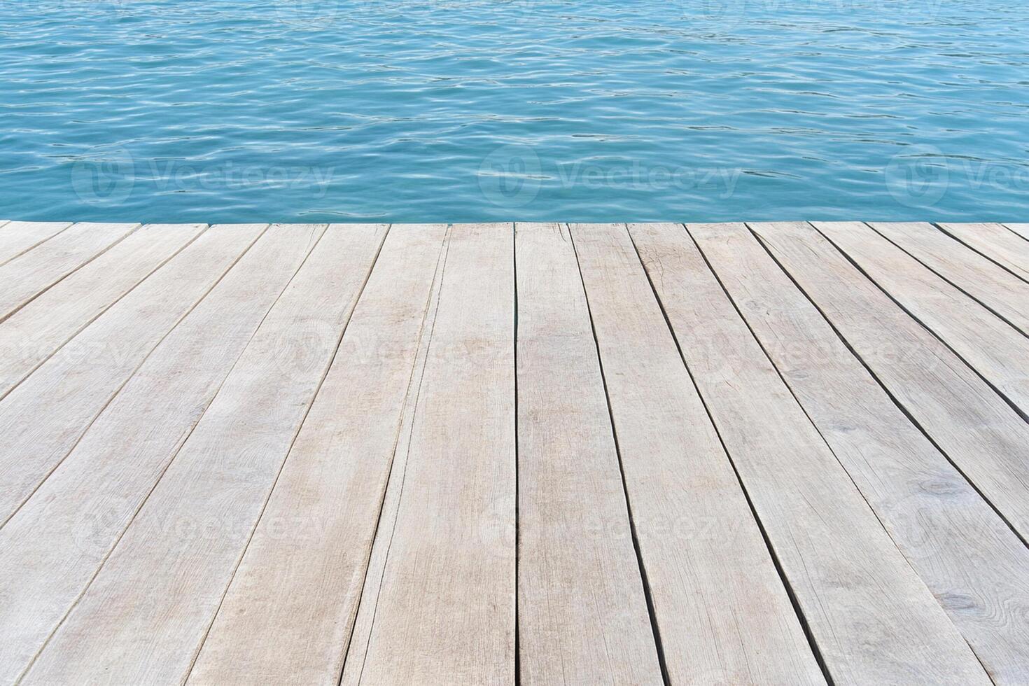 A wooden deck with a blue sky and water photo