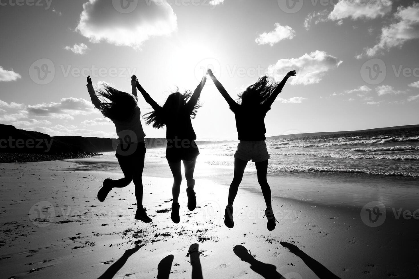Three girls jumping on the beach with their hands up photo