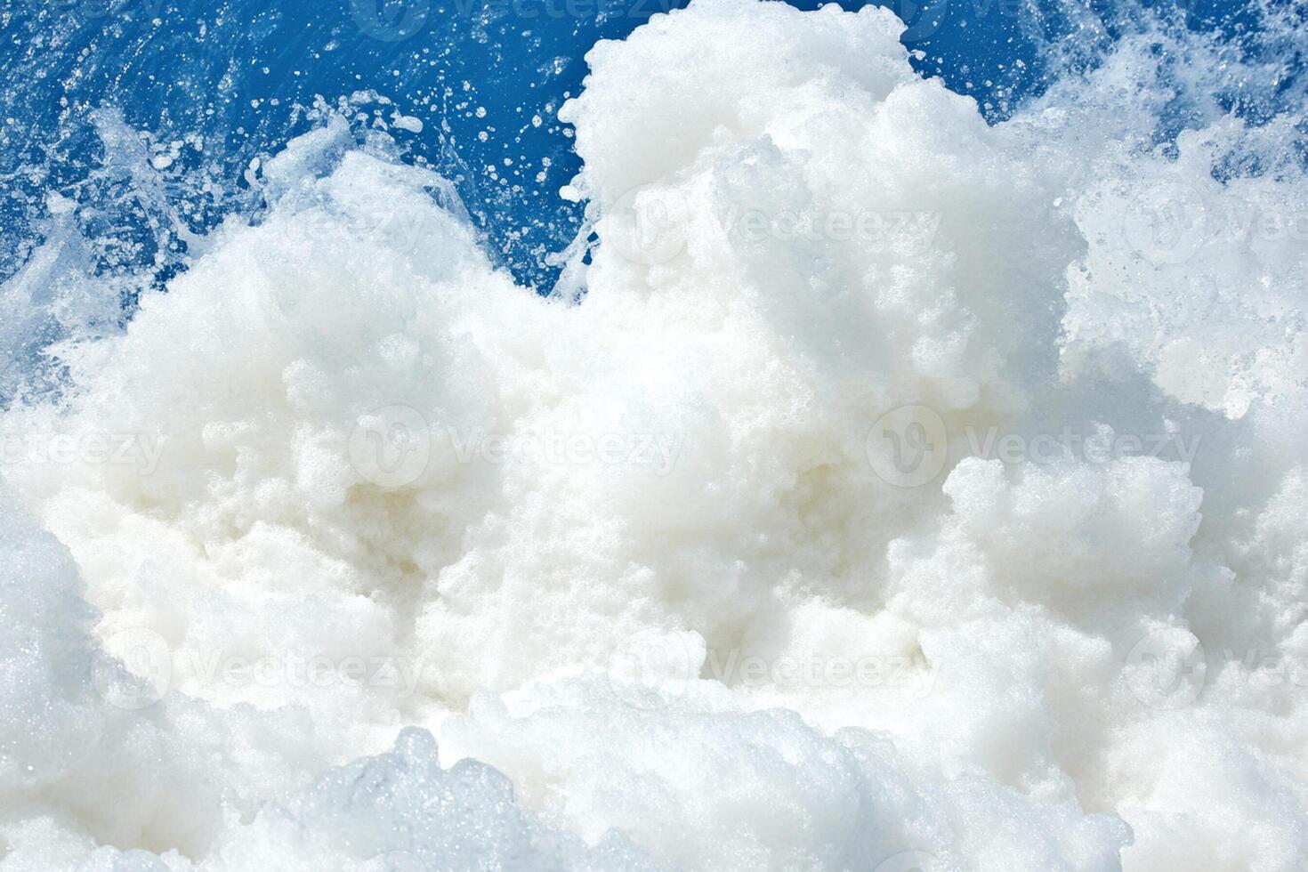 A white foam is being sprayed on a blue sky photo