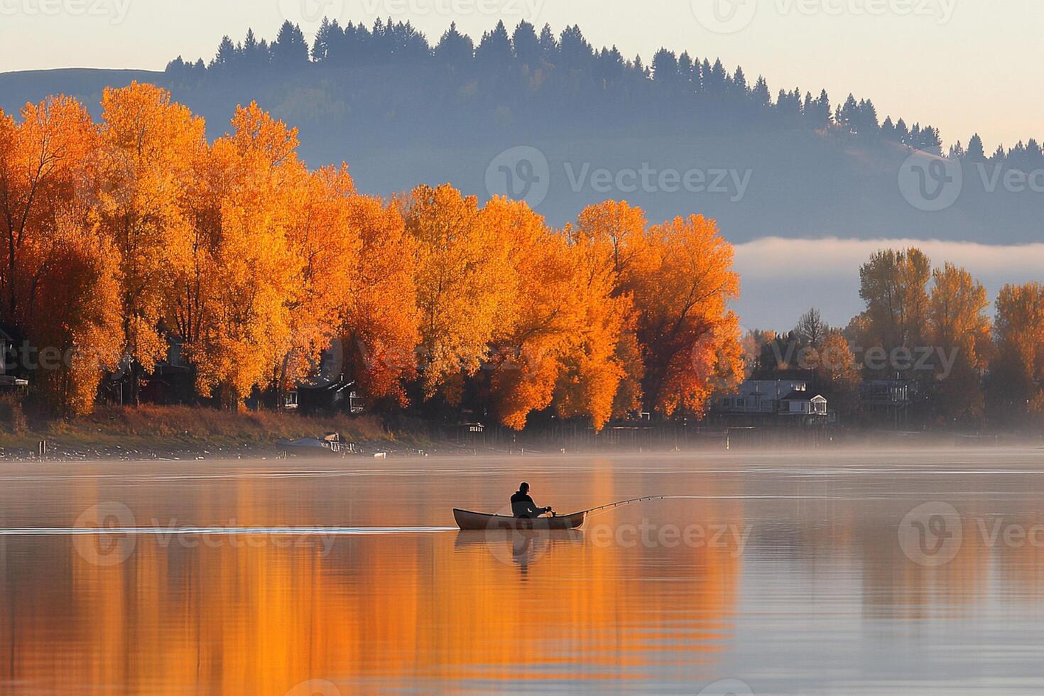 A man in a boat on a calm lake with trees in the background photo
