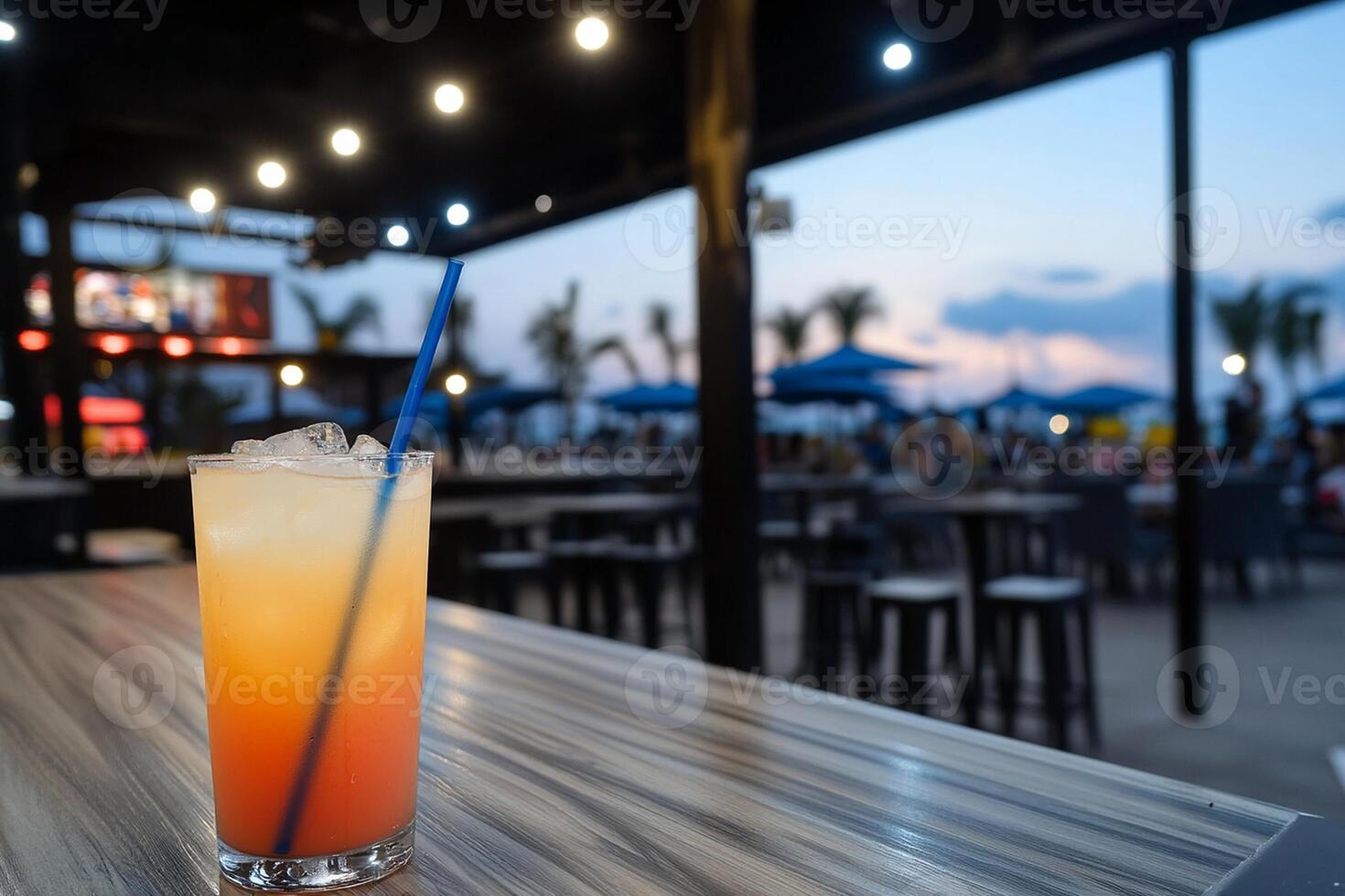 A drink sitting on a bar with a blue straw photo