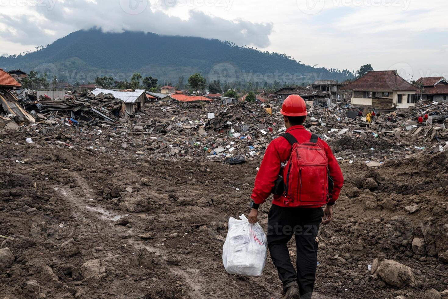 A man in a red shirt and red backpack walking through a dirt road photo
