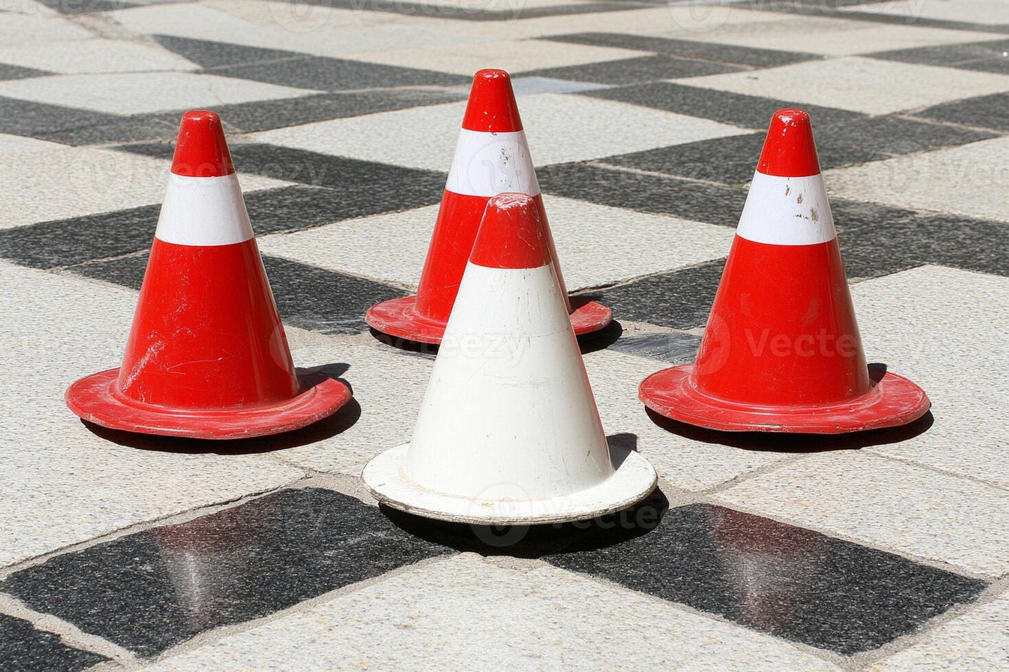 A group of four traffic cones on a sidewalk photo