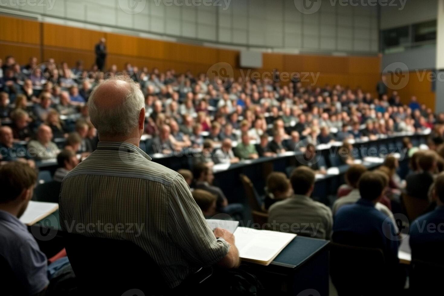 A man in a wheelchair is sitting in front of a large audience photo