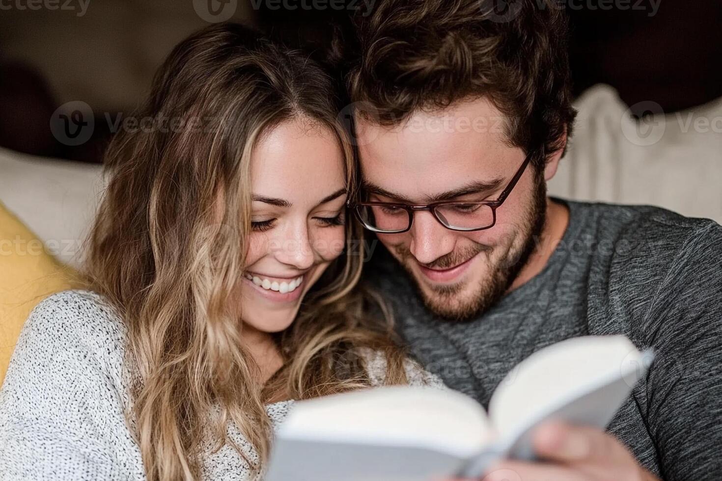 A man and woman are smiling while reading a book photo