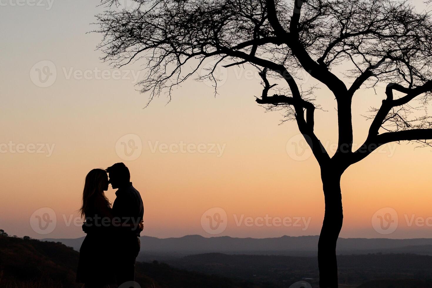 A couple kissing in front of a tree photo