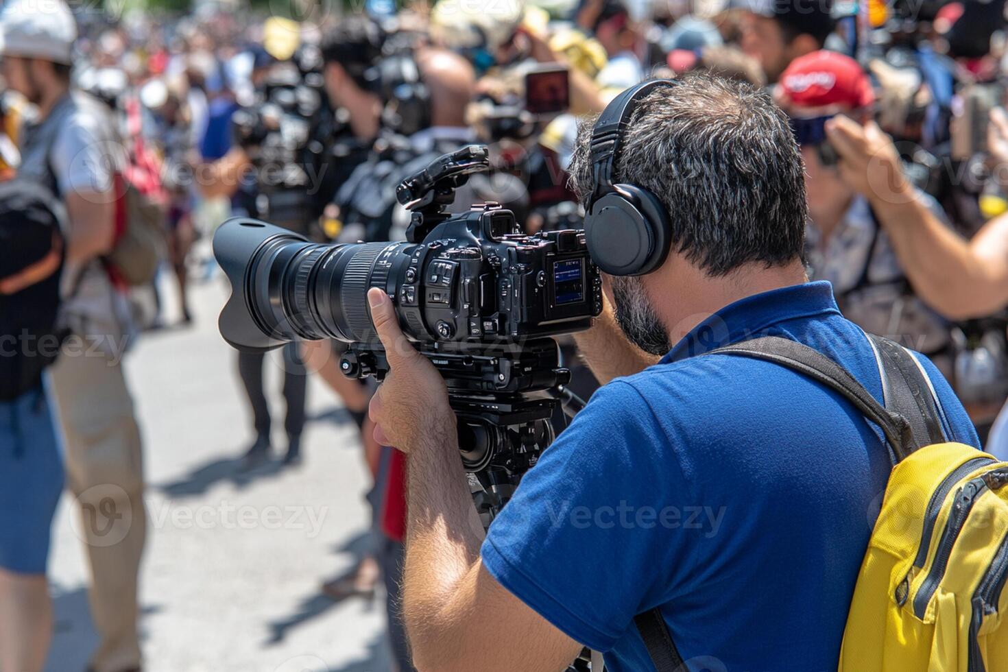A man with a camera and a backpack is taking pictures of a crowd photo