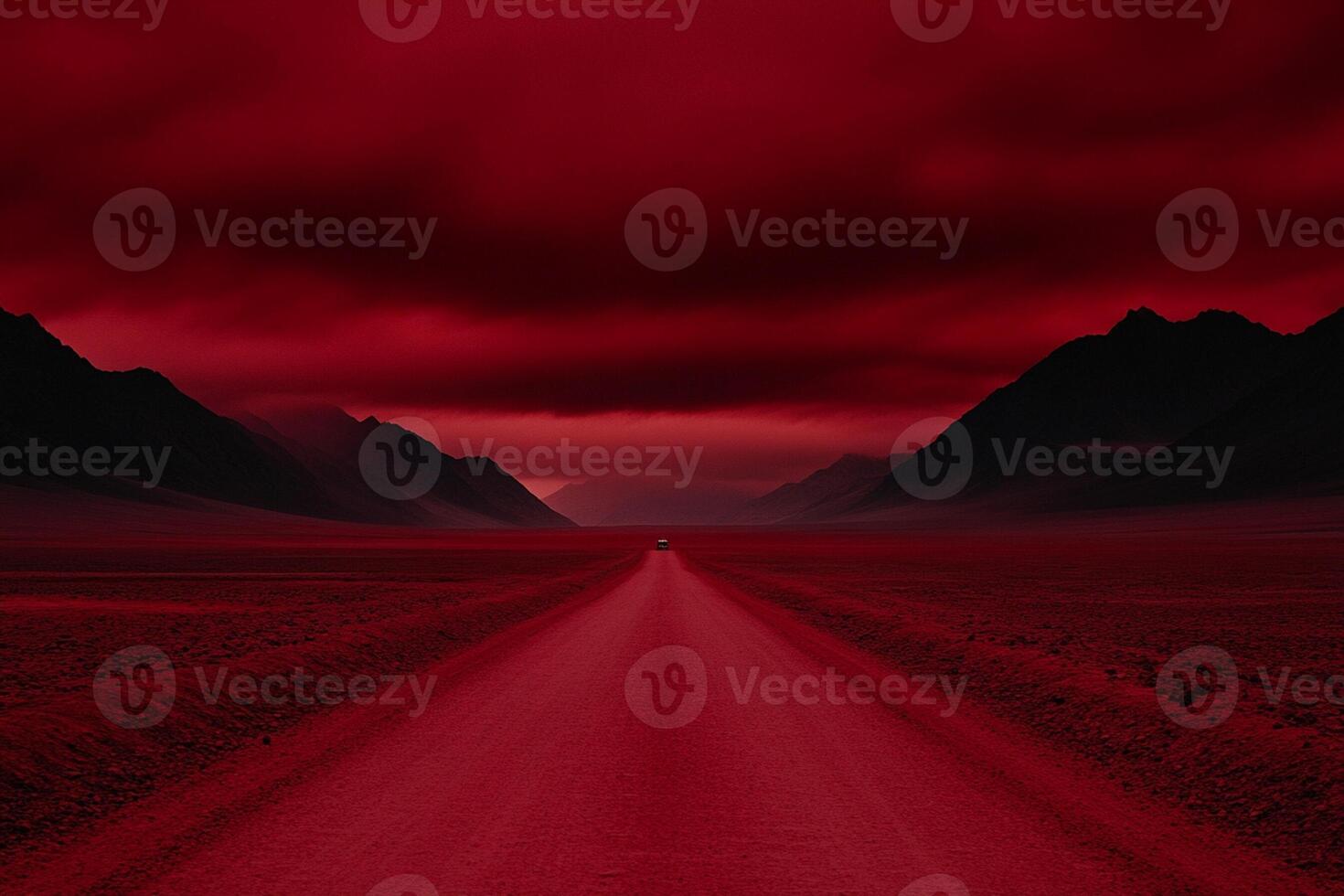A red road in the middle of a desert with mountains in the background photo