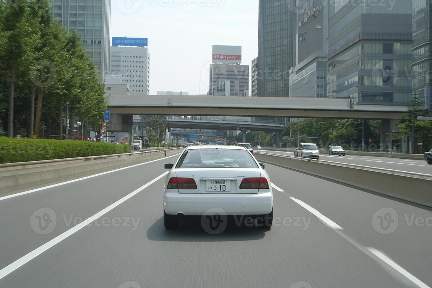 A car driving on a highway with tall buildings in the background photo