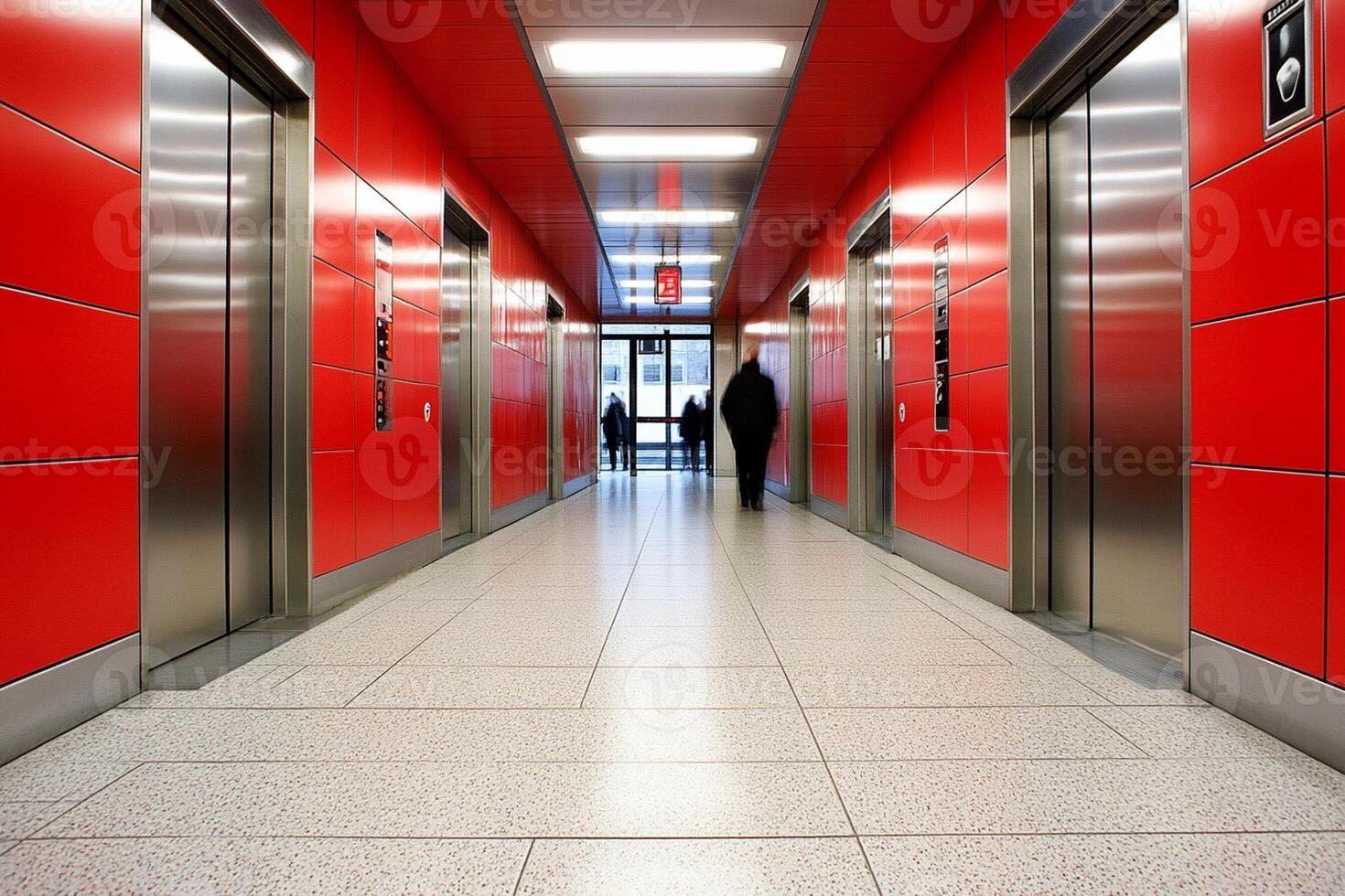 A person is walking down a hallway with two elevators photo