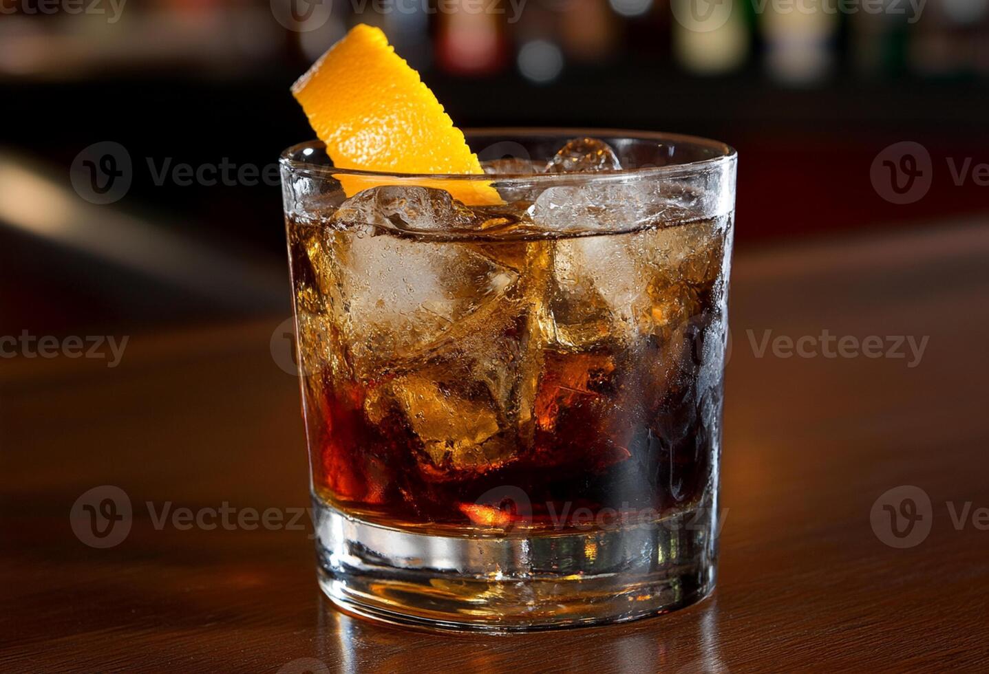 A glass of whiskey with ice and orange peel photo