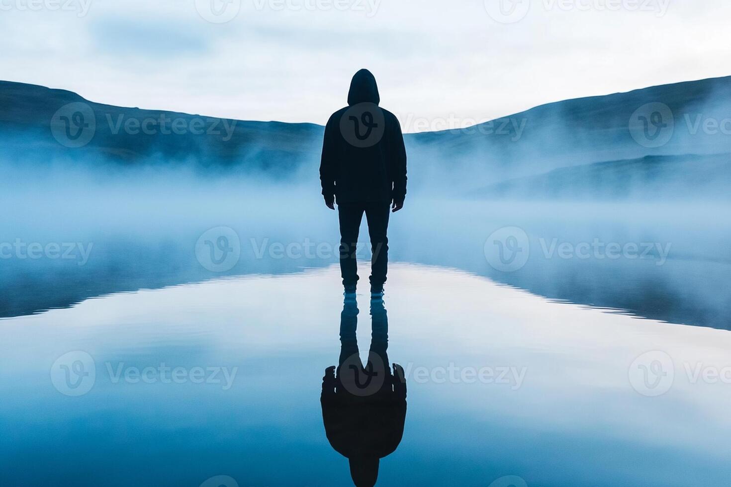 A person standing in the middle of a lake with fog photo