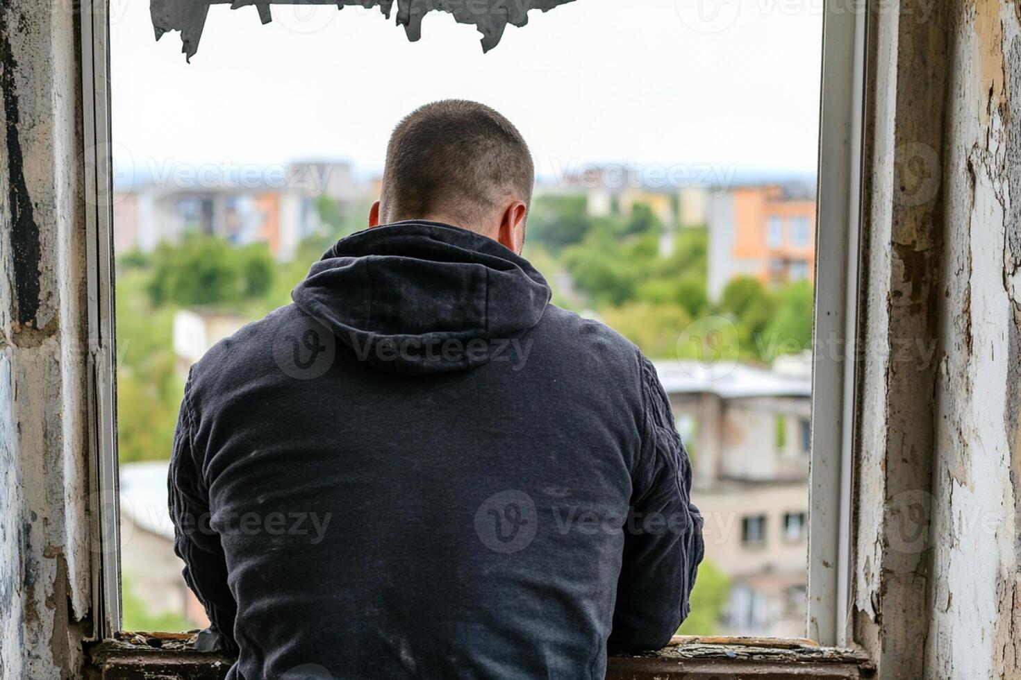 A man looks out a window at a city photo