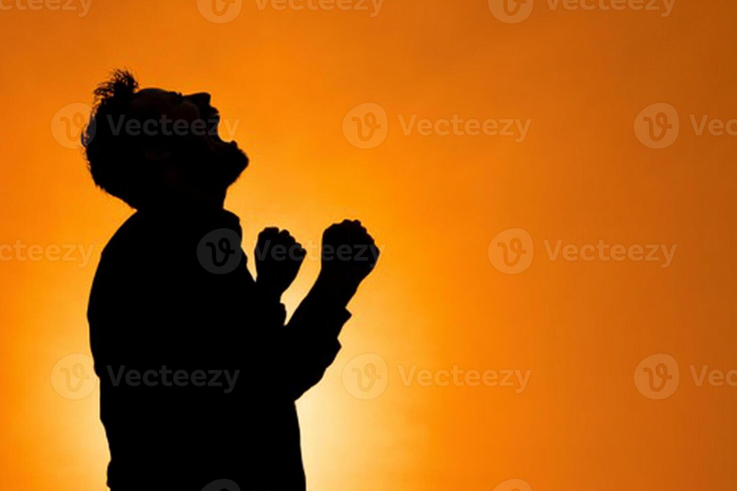 Silhouette of a man with his hands raised in the air photo