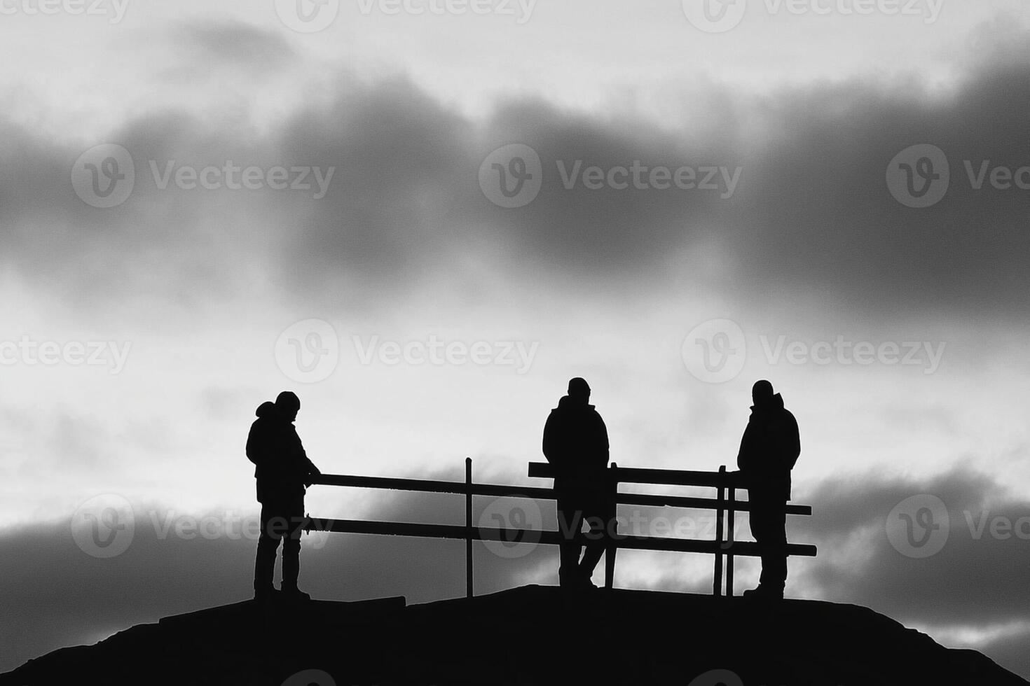 Three people standing on a hill with a fence photo