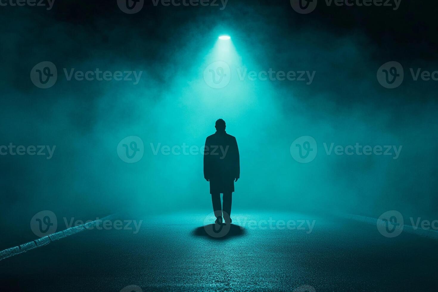 A man standing in the middle of a dark road with a light shining on him photo