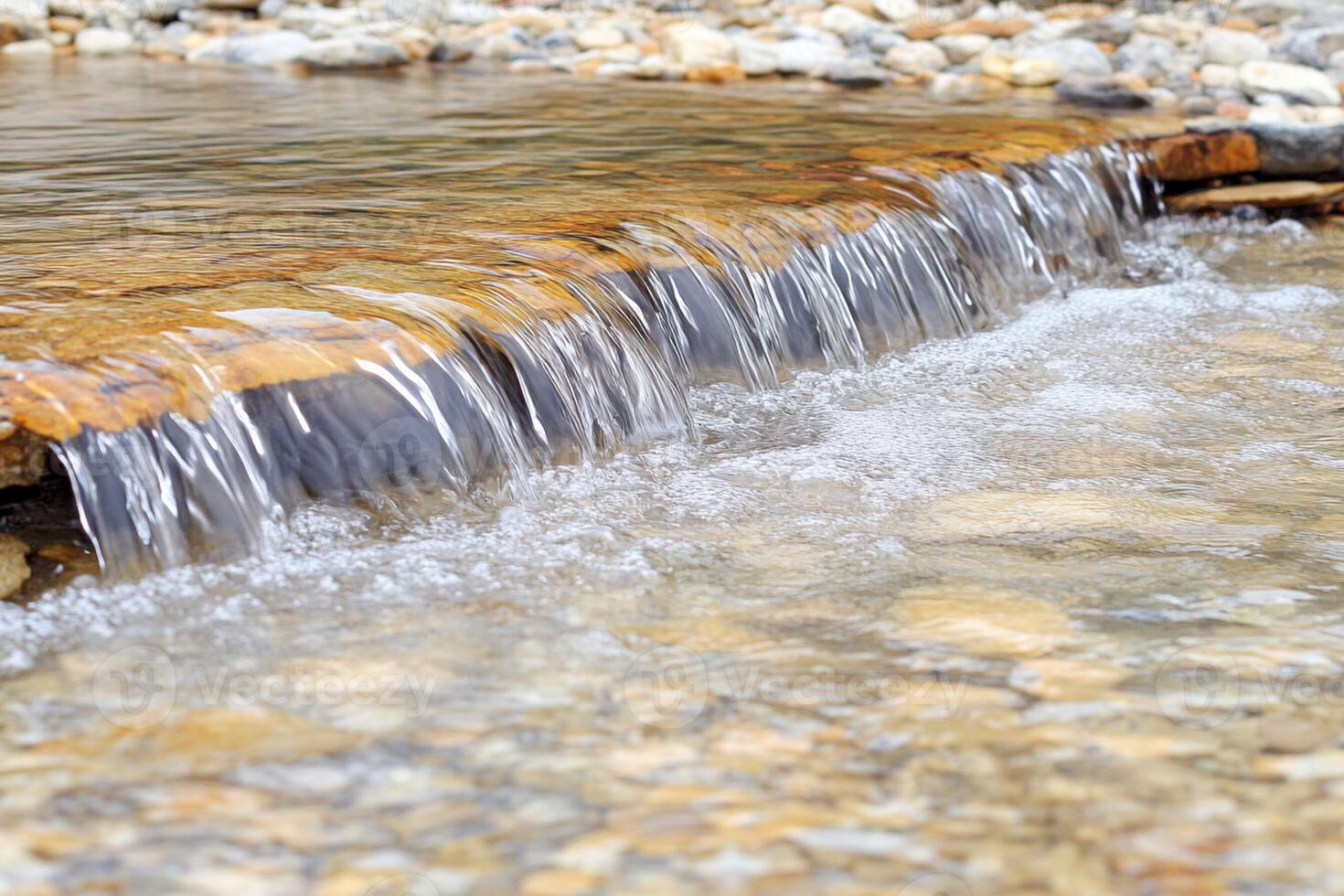 A small stream of water flowing over rocks photo