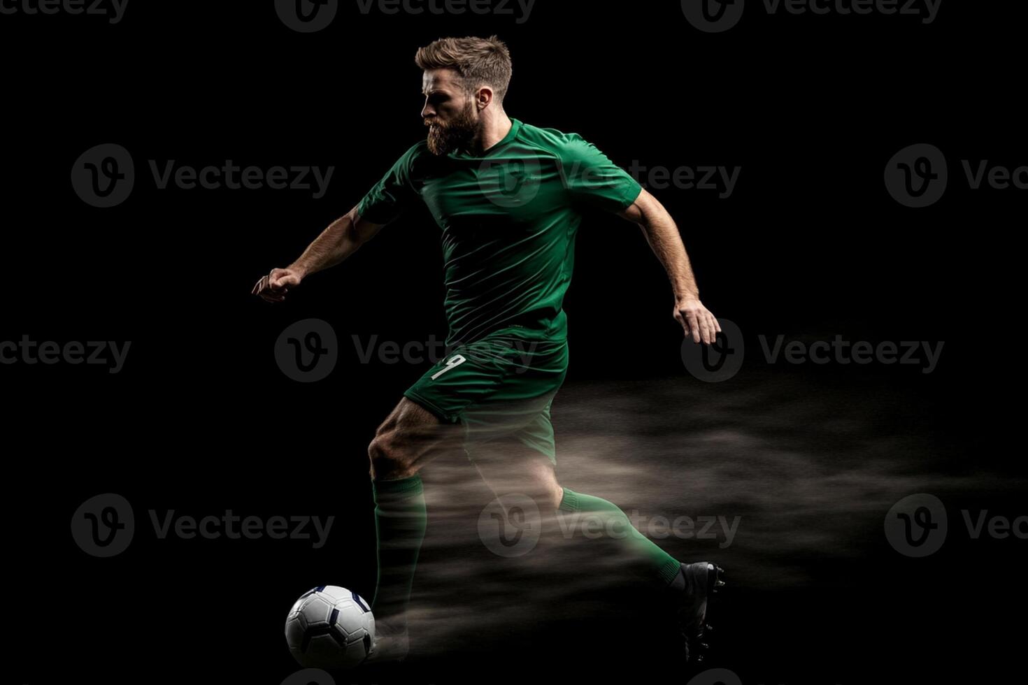 A man in green soccer uniform is kicking a soccer ball photo