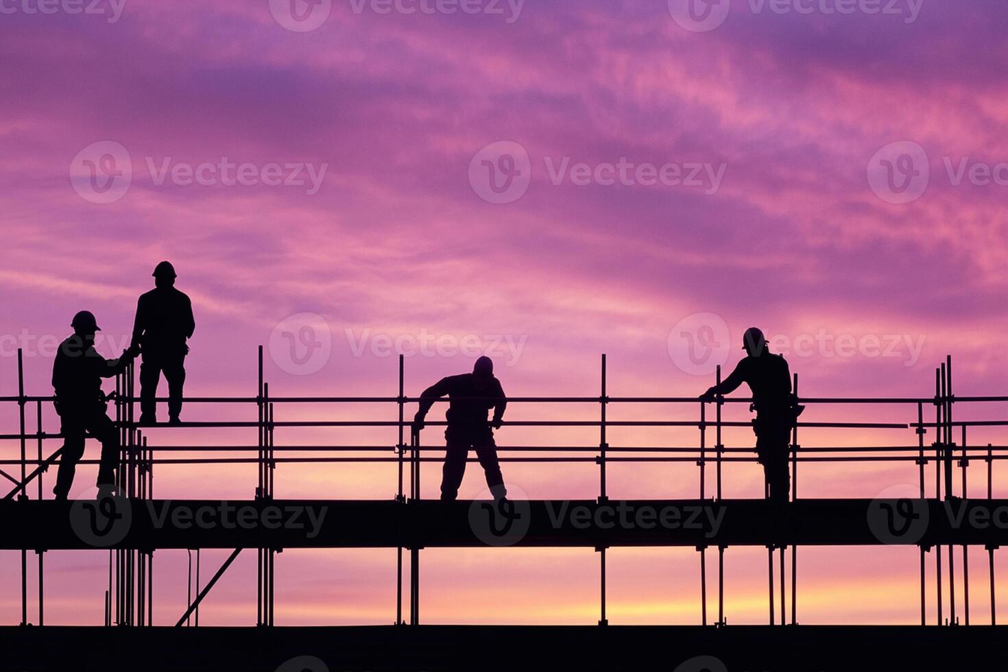 Construction workers on scaffolding at sunset photo
