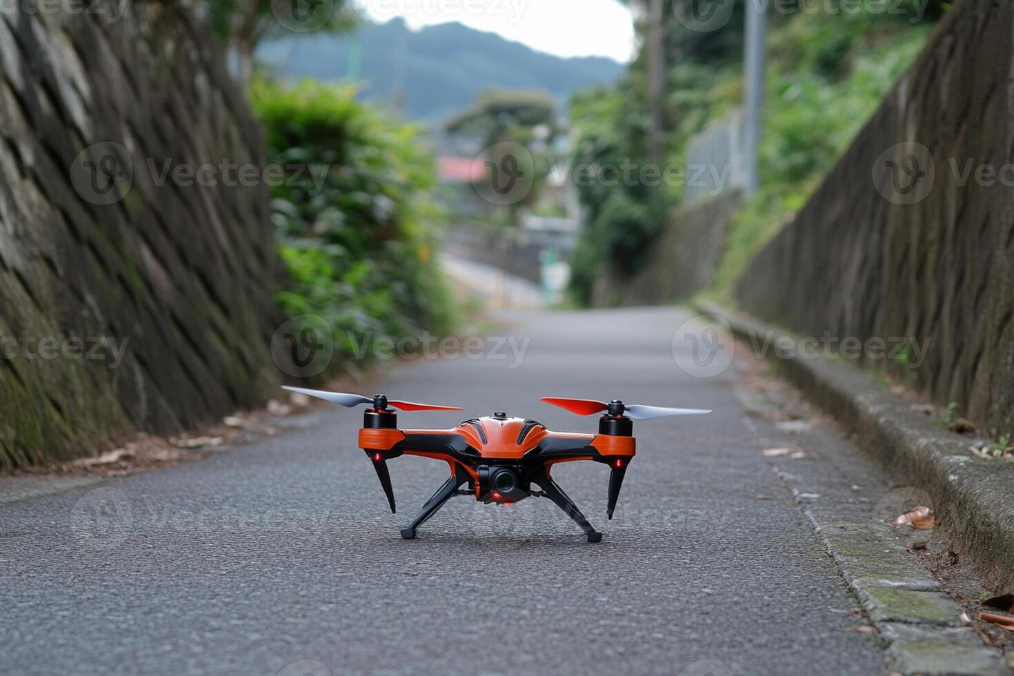 A small orange and black drone flying down a street photo