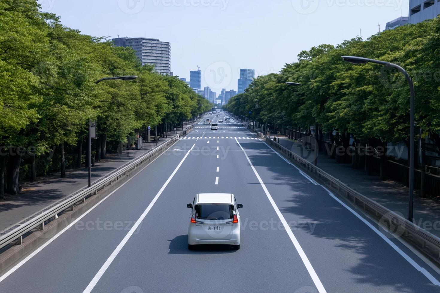 A white car driving down a road with trees in the background photo
