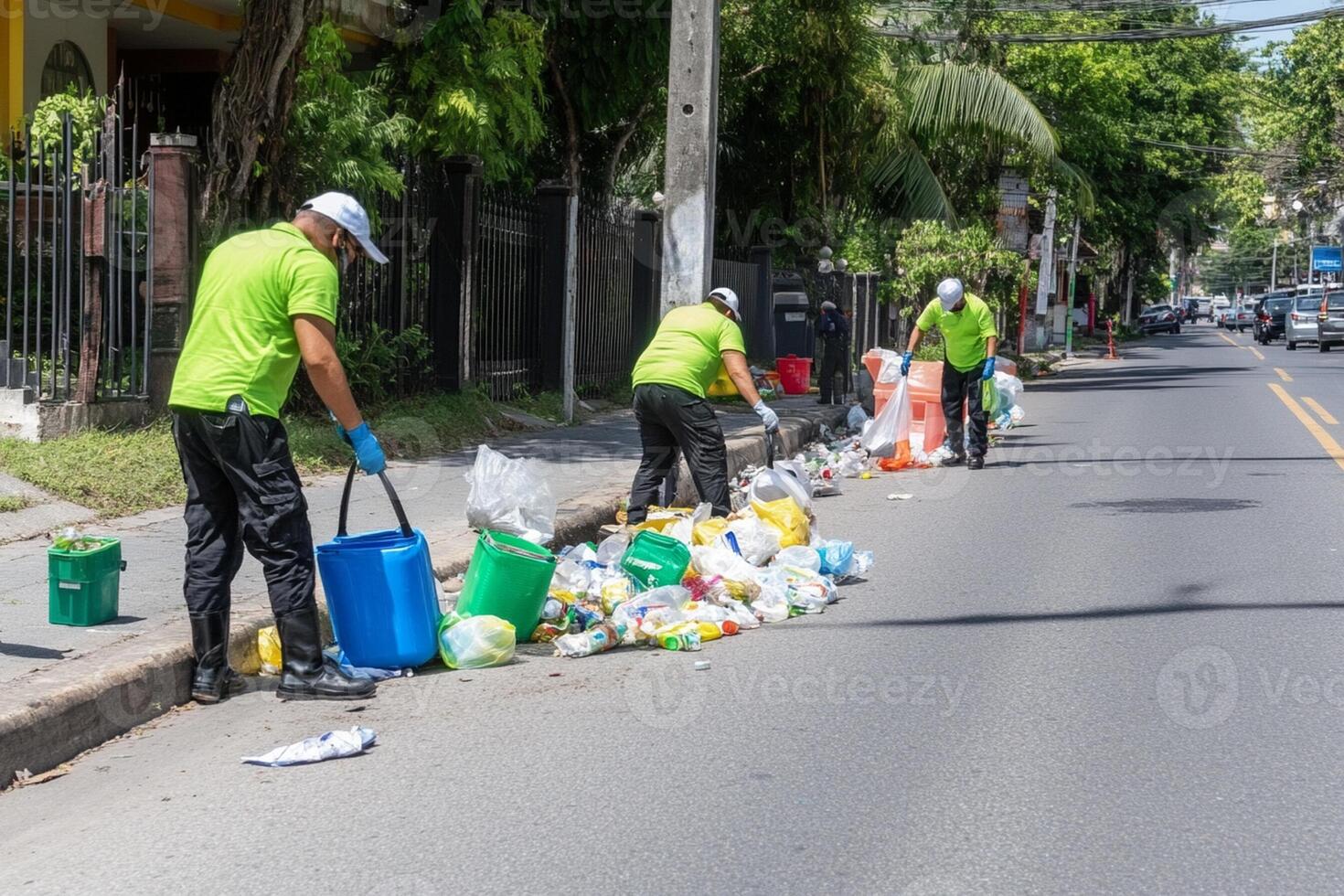 Three men in green shirts are cleaning up trash on the street photo